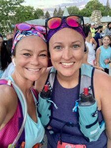 Kelley and a friend take a selfie before a race, with colorful headbands, sunglasses, and water bottles ready to go.