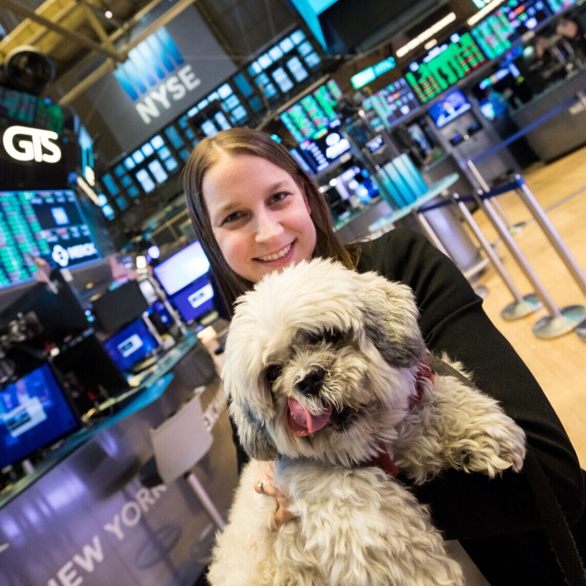 Rachel Herman, founder and Executive Director of PAWS NY, poses on the floor of the New York Stock Exchange with PAWS pup Bob after ringing the closing bell in November 2019.